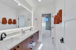 Full bath with double vanity, shower / bath combo with shower curtain, and light tile patterned floors