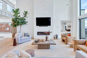 Living room featuring a high ceiling, a large fireplace, and wood finished floors
