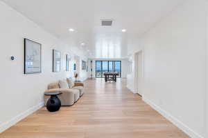 Hall with light wood finished floors and recessed lighting