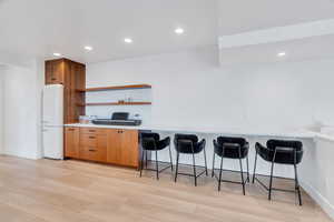 Kitchen featuring open shelves, recessed lighting, freestanding refrigerator, light countertops, and light wood-style flooring