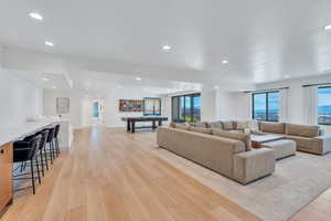 Living room with light wood-type flooring, recessed lighting, healthy amount of natural light, and bar area