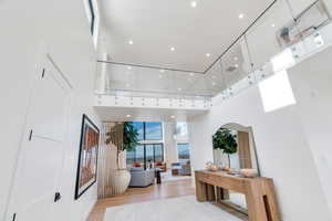 Hallway featuring recessed lighting, light wood-style flooring, and a high ceiling
