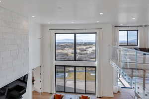 Unfurnished living room with a mountain view, a fireplace, recessed lighting, light wood-style flooring, and a high ceiling
