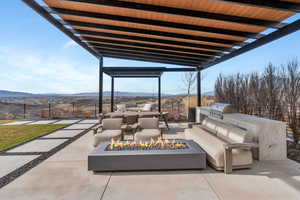 View of patio / terrace featuring a fire pit, a mountain view, an outdoor kitchen with living area, and a pergola