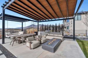 View of patio with a fire pit, an outdoor kitchen with living area, a mountain view, and a pergola