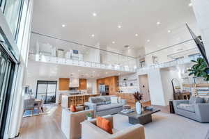 Living area with light wood-style floors, a high ceiling, and recessed lighting