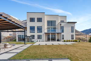 Rear view of property featuring a mountain view, a patio, stucco siding, and a balcony