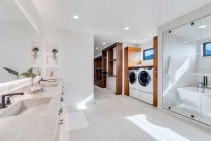Bathroom with double vanity, separate washer and dryer, a stall shower, recessed lighting, and a tub