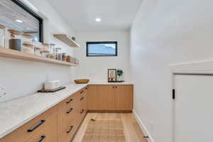 Bar with light stone counters, light wood-style flooring, open shelves, light wood finish cabinets, and recessed lighting