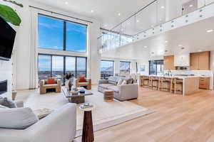 Living room with a high ceiling, light wood-style flooring, a fireplace, and recessed lighting