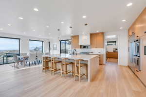 Kitchen featuring a kitchen bar, light stone countertops, light wood finished floors, a large island, and modern cabinets