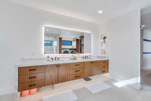 Ensuite bathroom with double vanity, a walk in closet, recessed lighting, and light tile patterned flooring
