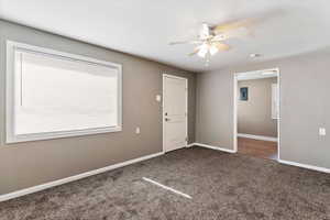 Foyer entrance with ceiling fan and dark carpet