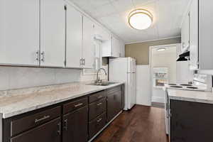 Kitchen with white appliances, light countertops, dual tone cabinets, dark wood-type flooring, and wainscoting