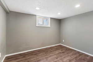 Below grade area with dark wood-style floors, a textured ceiling, and recessed lighting