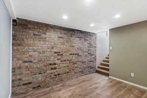 Finished basement featuring brick wall, light wood-style floors, and recessed lighting