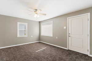 Spare room featuring a ceiling fan and dark colored carpet