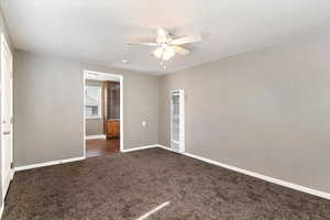 Unfurnished bedroom featuring a heating unit, dark colored carpet, and ceiling fan