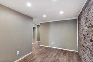 Empty room with wood finished floors, brick wall, and recessed lighting
