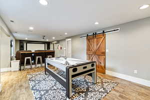 Playroom with light wood finished floors, recessed lighting, and a barn door