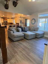 Living room with light wood-type flooring, vaulted ceiling, and suspended lighting