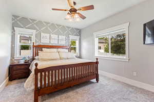 Master bedroom with an accent wall, ceiling fan, and carpet floors