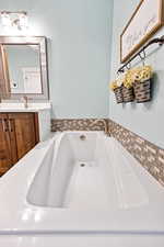 Bathroom featuring vanity, a garden tub, and a textured wall