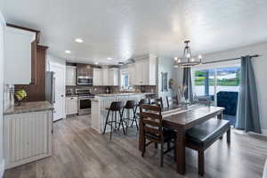 Dining room with hanging lights, plenty of natural light, light wood-style floors, and a textured ceiling