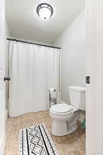 Bathroom with curtained shower and light tile patterned floors