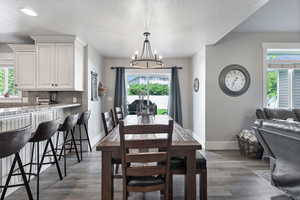 Dining space featuring a chandelier, plenty of natural light, dark wood-style floors, and a textured ceiling