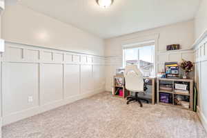 Office/bedroom area featuring a decorative wall, wainscoting, and light carpet