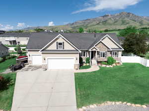 Craftsman-style house featuring stone siding, a mountain view, driveway, roof with shingles, and an attached garage