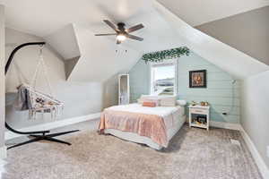 Carpeted bedroom with ceiling fan and lofted ceiling