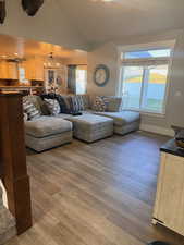 Living room with wood finished floors, vaulted ceiling, and a chandelier