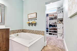 Full bathroom with a garden tub, vanity, parquet flooring, and a spacious closet
