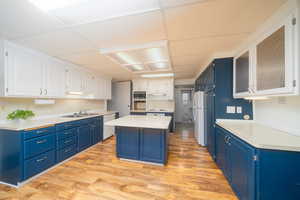 Kitchen featuring two tone color scheme, light countertops, light wood-style floors, white appliances, and a kitchen island