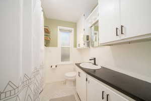 Full bath with vanity, a shower with shower curtain, and a wainscoted wall
