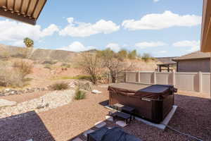 Fenced backyard with a hot tub, a patio, and a mountain view