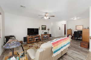 Living room featuring a desk, light wood-style flooring, and ceiling fan