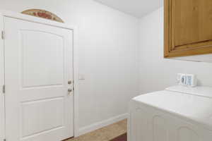 Laundry room featuring washer / clothes dryer, cabinet space, and light tile patterned floors