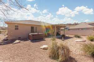 Rear view of property featuring a hot tub, a patio, a tile roof, crawl space, and stucco siding