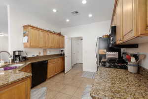 Kitchen with light stone countertops, black appliances, light tile patterned floors, and recessed lighting