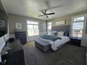 Master Bedroom with dark carpet, a wainscoted wall, a ceiling fan, and a textured ceiling,
