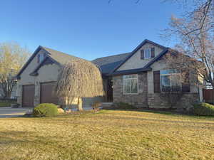 View of front of property featuring stucco siding, stone siding, a front lawn, and concrete driveway