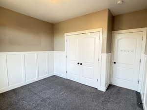 Bedroom 1/5 with a wainscoted wall, dark gray carpet, a wider closet, 9 ft ceilings