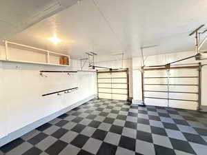 Garage with a garage door opener, man door, shelves and awesome rubber floor.