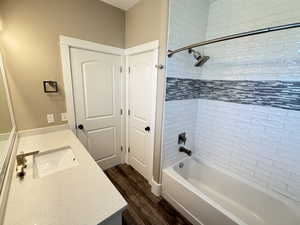 Master bath featuring custom vanity, quartz countertop, LVP floors, tub-shower with custom tiled walls, large linen/storage closet