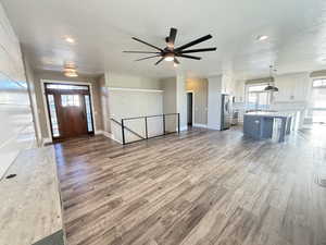 Great room featuring recessed lighting, modern fan, LVP-type flooring, large windows and accent wall with built in floating shelves.