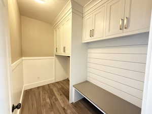 Laundry/Mudroom featuring a wainscoted wall, custom cabinets, convenient bench with storage area underneath, skiplap accent wall