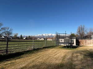 Fenced backyard with a trampoline and a west mountain view